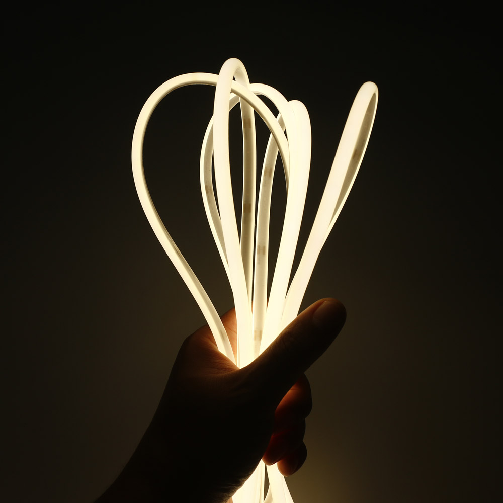 Flexible Φ7mm semi-circular COB LED strip light glowing warm white, held by hand for bendability demonstration